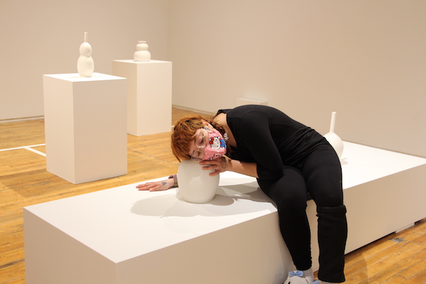 A display of Seo Hye Lee's sculptures on plinths. A visitor has their ear to one of the sculptures.