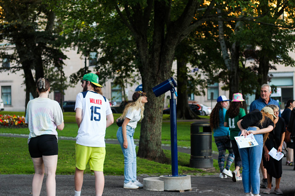 Person peering through blue telescope installation