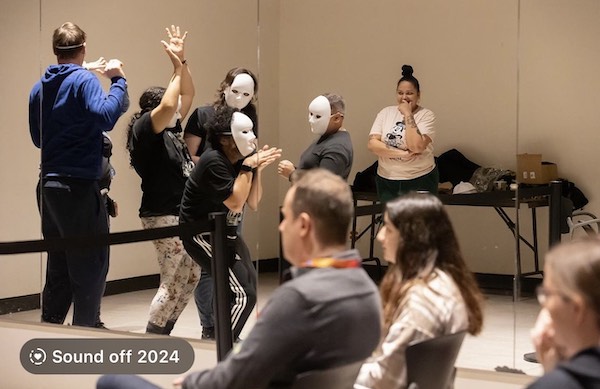 Gaitrie Persaud-Killings directs a group of masked actors in a performance of The Red Rose Bleeds.