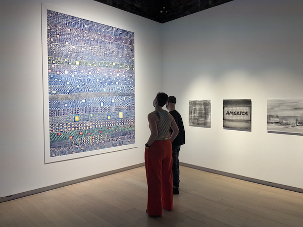 Installation view of the Bucko Art Machine survey exhibition at SAW gallery. Two visitors are looking at a large colourful abstract painting.