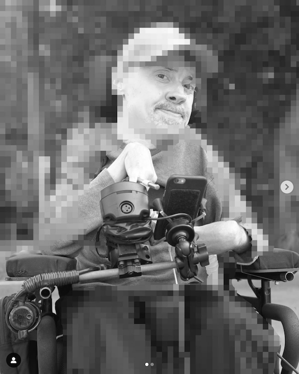 Black and white photograph of Chris Binkowski (aka Bucko Art Machine) sitting in his wheelchair. The image is pixelated around the edges.