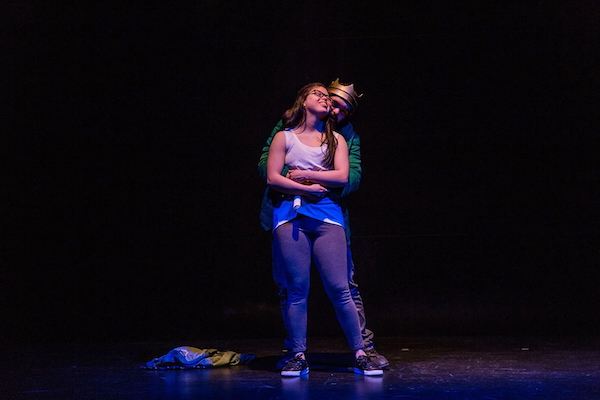 Two actors on stage, one as Hamlet, the other as Ophelia, hug each other.