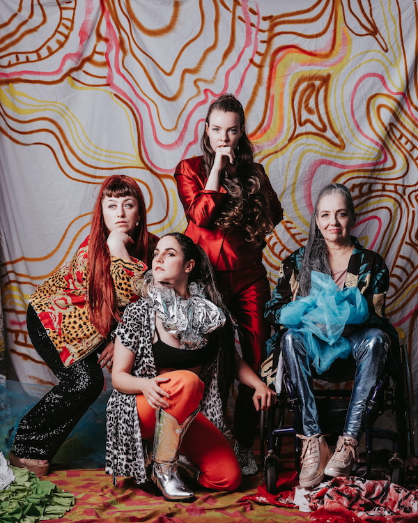 Four members of Ottawa's Ghost Rooster Collective are photographed wearing brightly coloured clothes in front of a painted backdrop.