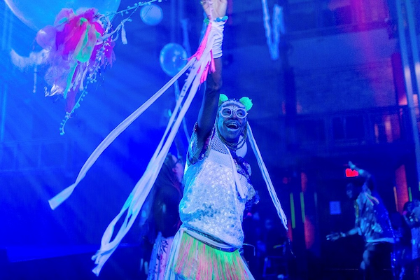 A photograph of a person dressed for a rave and dancing at a club.