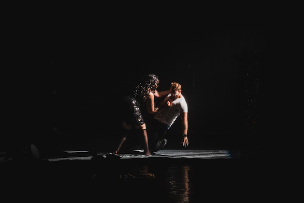 On a dark stage, a woman is seen stabbing a man.