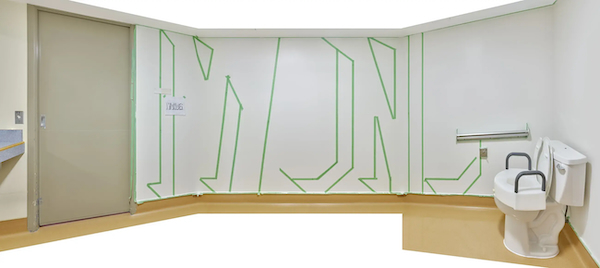 An accessible bathroom with letters reading "I WON" taped off in green on a white wall.