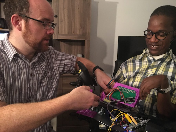 Two men are depicted facing each other and working on a piece of electronic equipment.