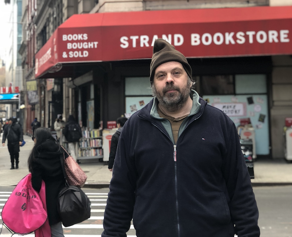 Shane Neilson is a bearded man wearing a toque and a winter jacket. He is standing in front of the Strand Bookstore.