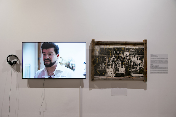 Michel Dumont’s Mission Indian Day School, 2020, is a ceramic tile mosaic of a 1950s classroom photograph of Indigenous children and teachers, framed in rough cedar and repaired with visible gold seams. A nearby monitor and headphones show documentation of the performance in which the artist breaks and reconstructs the image.