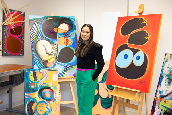 A person standing between two easels with large paintings on them