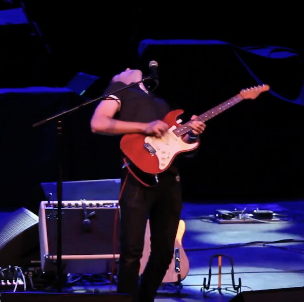 Lucas Haneman playing electric guitar live on stage. He is bending back, mid-solo, so you can't see his face.